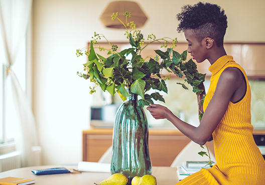 Woman wearing yellow dress arranging flowers in a vase