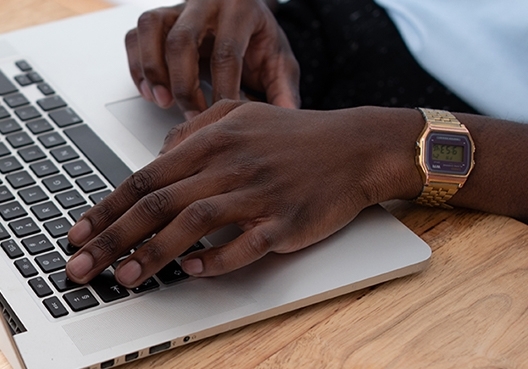 A picture of a man's hands on a laptop keyboard